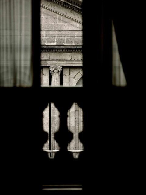 <b>Luz a cuchillo.</b> Window behind the balustrade of the National Gallery of Art facing a portion of the main façade of the Colegio de Minería, Mexico City (2007).